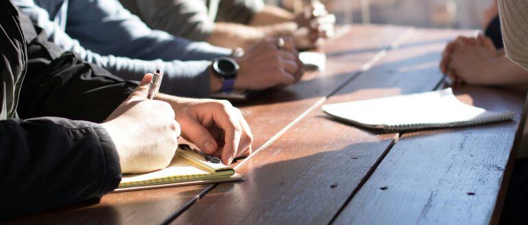 several people's hands and notebooks on a work desk